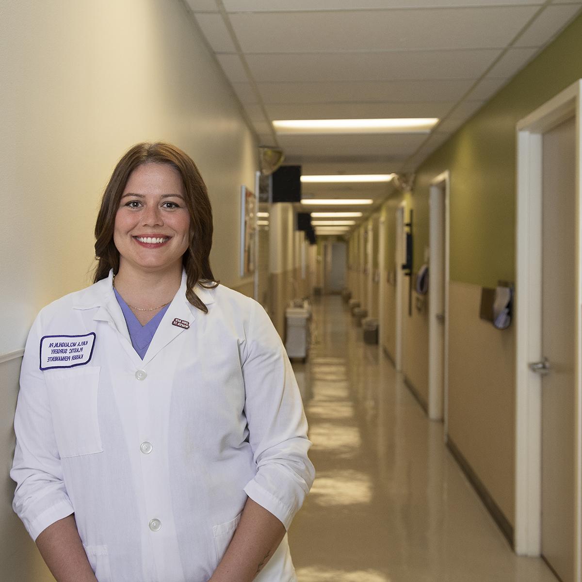 Photo of Kayla McLaughlin in a white smiling in a hospital corridor